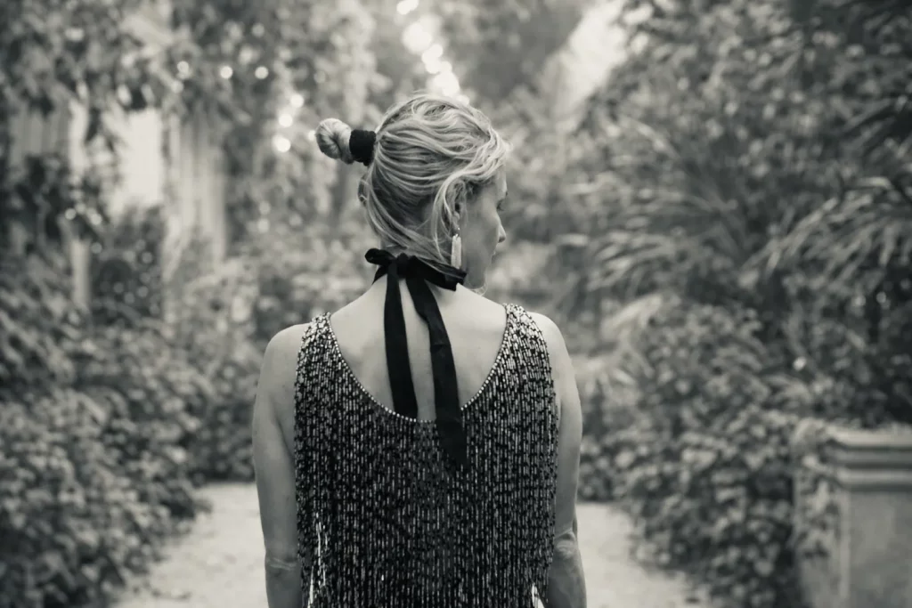 Black-and-white photograph of Meggen Harris seen from behind outdoors, wearing a dress with a large bow.